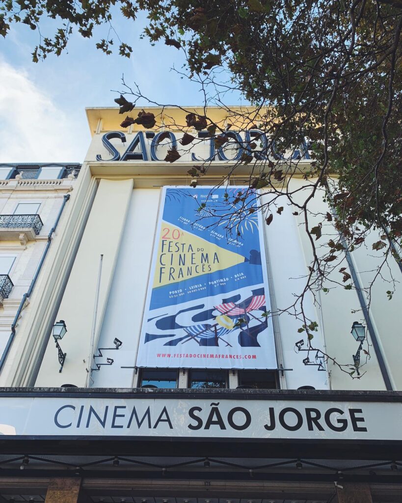 Historic Lisbon cinema São Jorge showcasing a vibrant poster for the French Cinema Festival, surrounded by lush trees and classic architecture, perfect for springtime cultural outings.