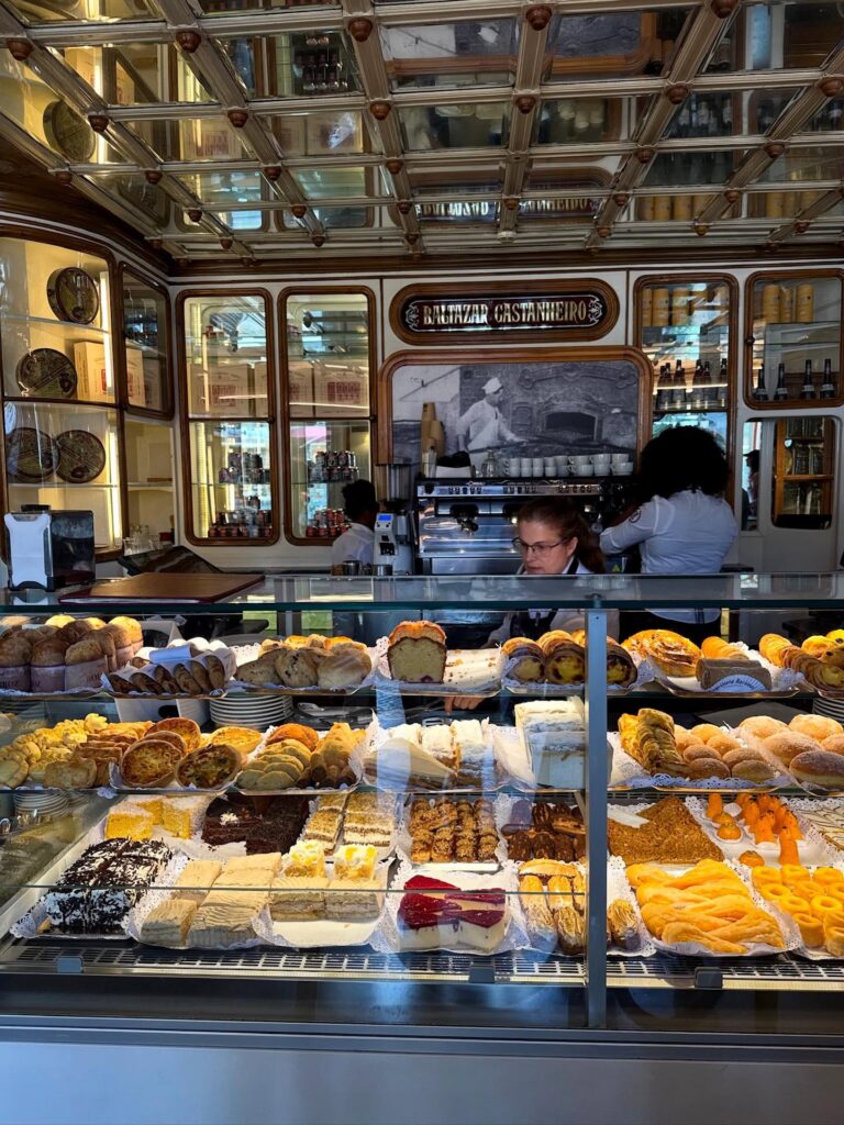 Buttery pastries and cakes displayed in a glass case at a traditional Portuguese bakery in Lisbon, showcasing authentic local desserts and baked goods in a charming setting.