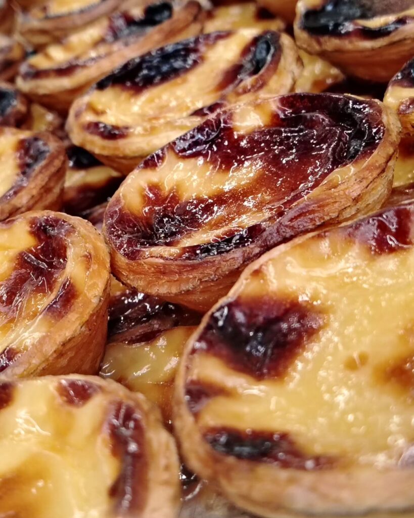 Lisbon in April: The Perfect Time To Visit 6 Delicious Portuguese custard tarts, also known as "Pastéis de Nata," showcasing their golden, flaky pastry and creamy custard filling, perfect for a Lisbon visit in April.
