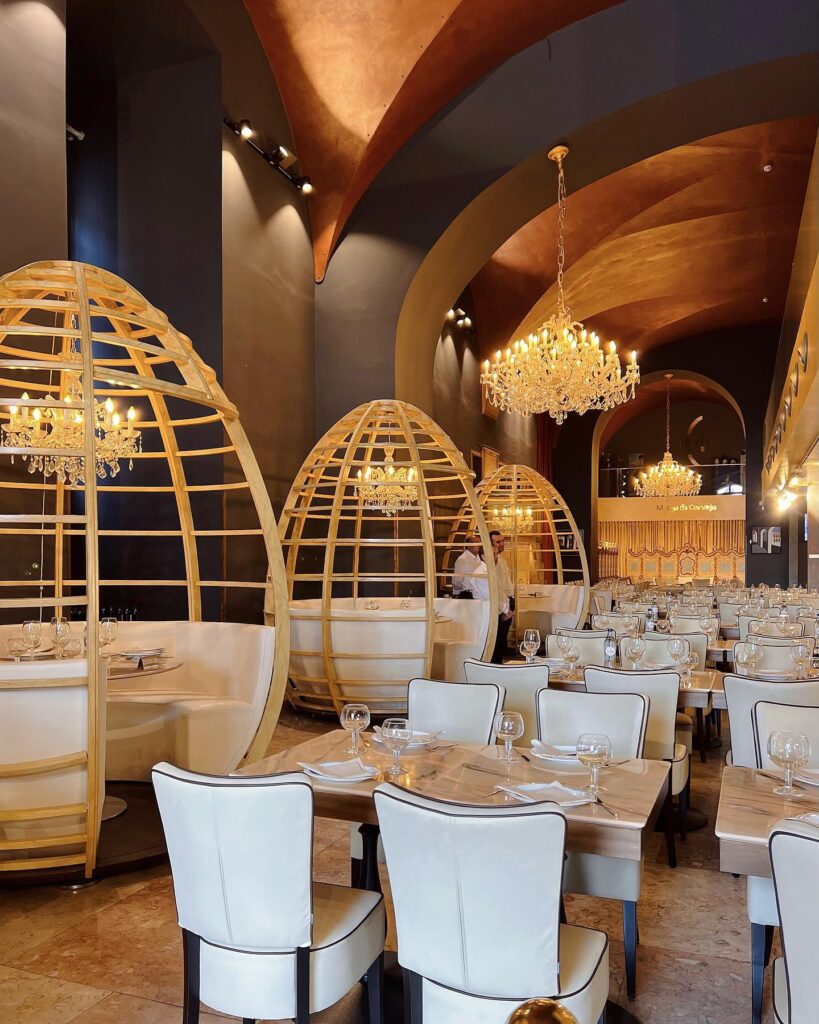 Luxurious dining space in Lisbon featuring cozy, cocoon-like booths, elegant chandeliers, and stylish decor, perfect for a memorable culinary experience in the heart of Lisbon.