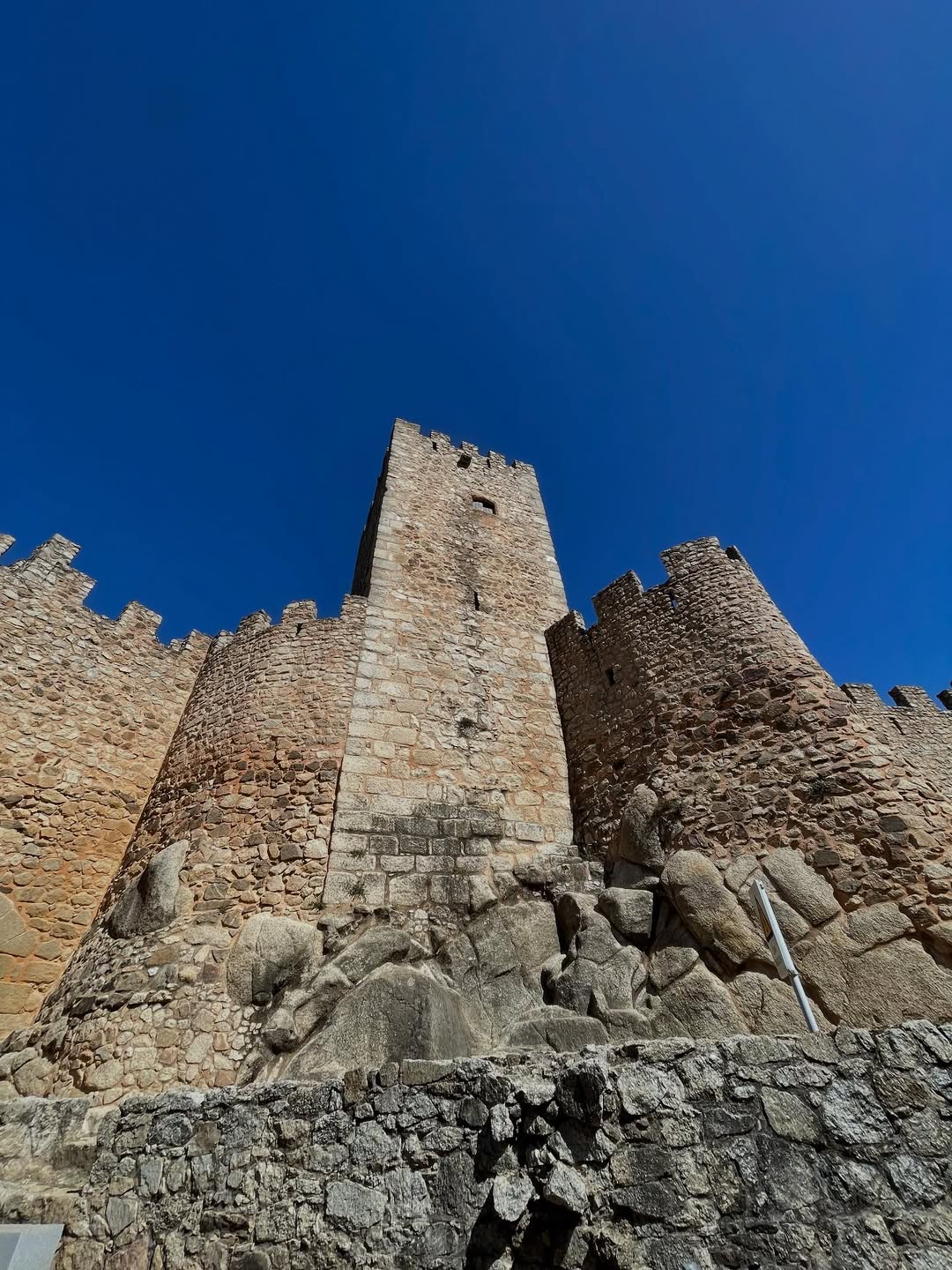 21 Amazing Castles in Lisbon and Its Surroundings 15 Ancient Castelo de São Jorge with stone walls and tower under a clear blue sky, a iconic landmark in Lisbon, Portugal, showcasing the city's rich history and medieval architecture.