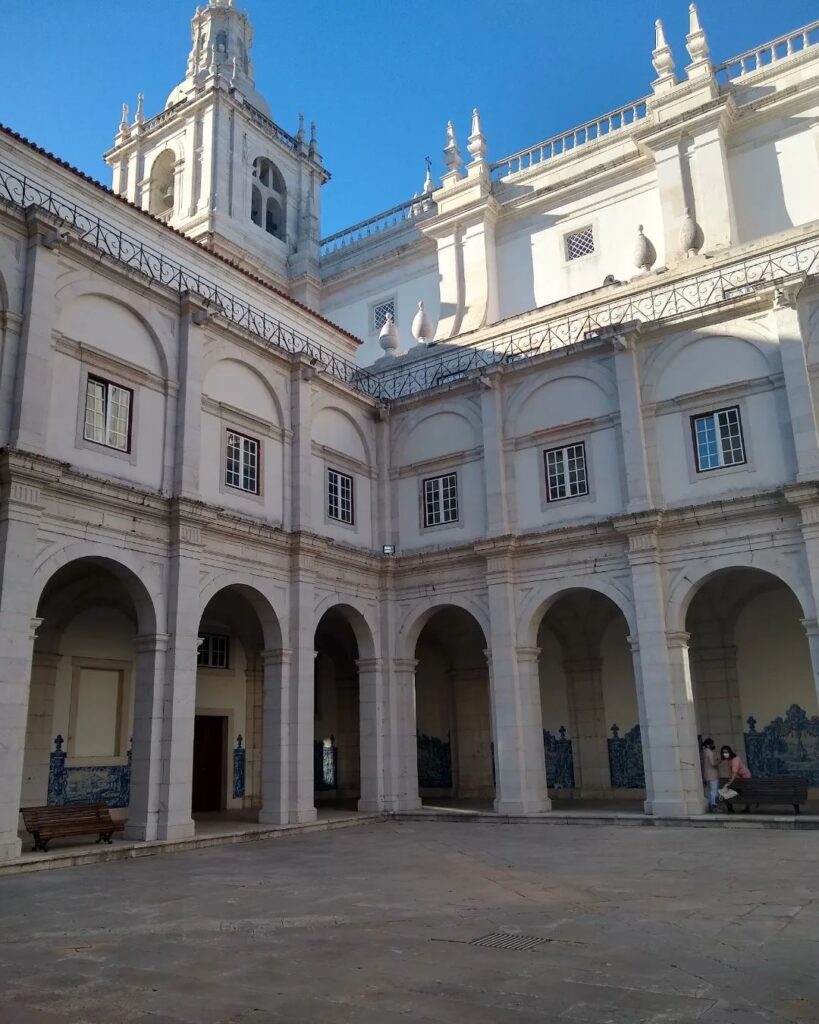 Alfama in Lisbon features historic white buildings with elegant arches and a bright blue sky, showcasing the charm of Lisbon's oldest district.