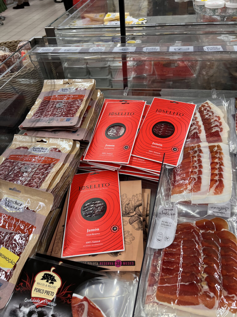 Up of packaged meats and cured ham at a Lisbon supermarket, showcasing local shopping options for fresh and traditional products.