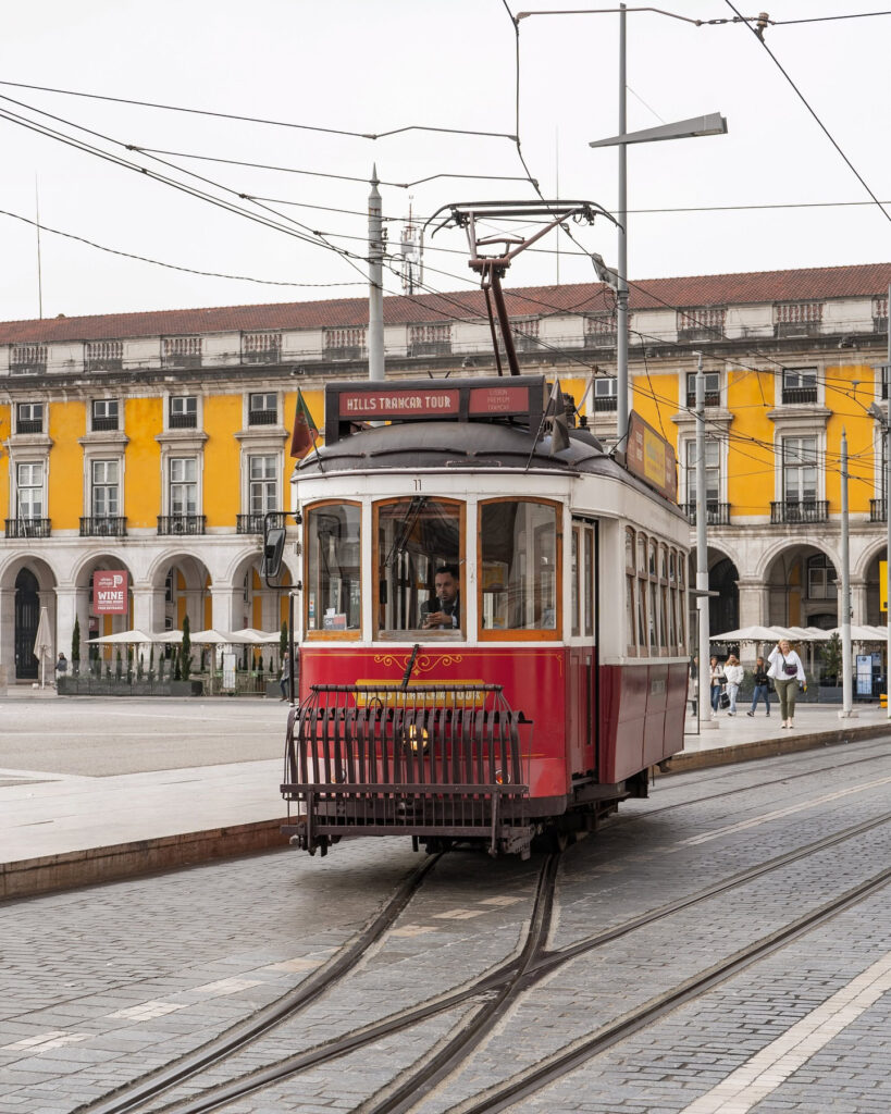 Vintage Lisbon Tram 28 on city streets, showcasing iconic yellow and red colors, historic architecture, and tram tracks in Lisbon, Portugal.