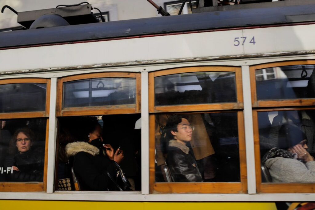 Iconic Lisbon Tram 28 with passengers enjoying a scenic ride through historic Lisbon streets. Perfect for exploring Portugal's vibrant culture and charming neighborhoods.