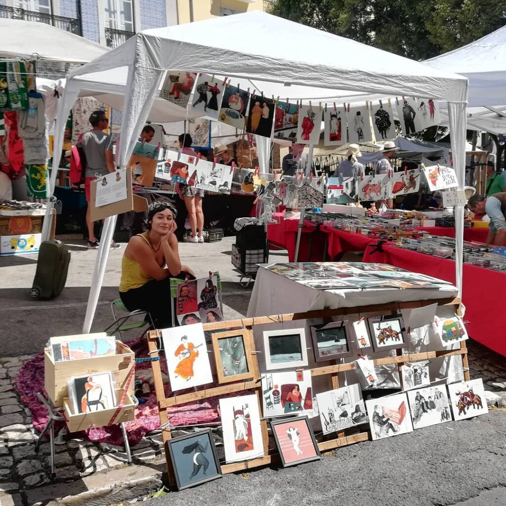 Vibrant art display at Graça Lisbon market showcasing local artists' work, including paintings, illustrations, and crafts, perfect for visitors exploring Lisbon's artistic neighborhoods.
