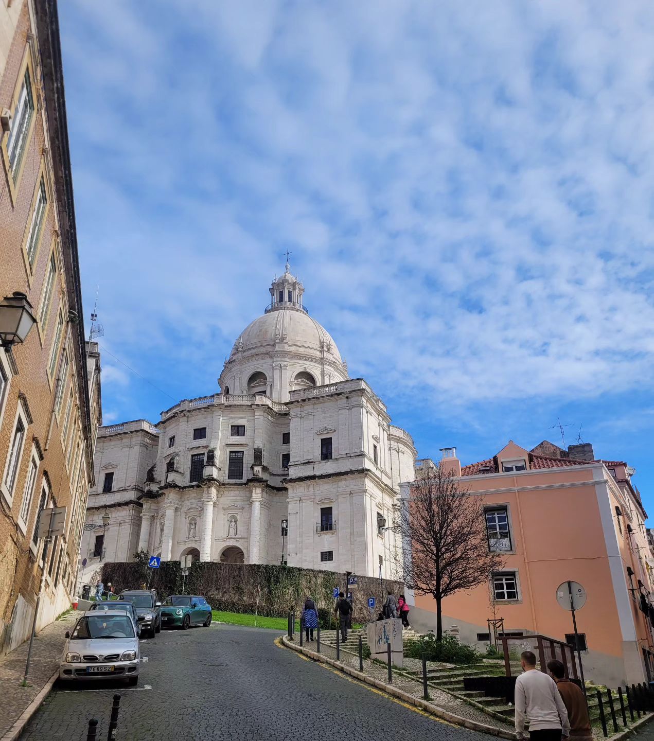 Iconic Lisbon Cathedral on a sunny day with vibrant city streets and blue sky, showcasing Lisbon's historic architecture and lively atmosphere.